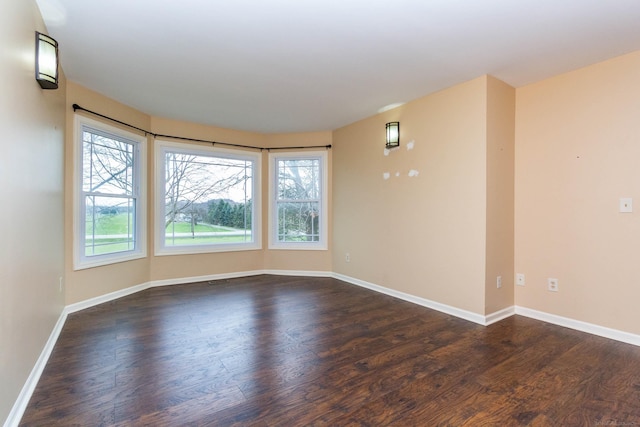 spare room featuring baseboards and dark wood-type flooring