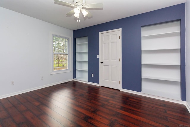 unfurnished bedroom with multiple closets, baseboards, wood finished floors, and ceiling fan