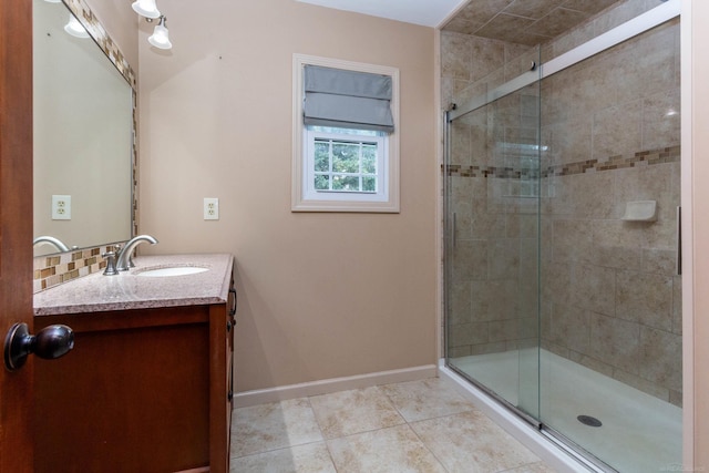bathroom featuring baseboards, vanity, tile patterned flooring, and a stall shower