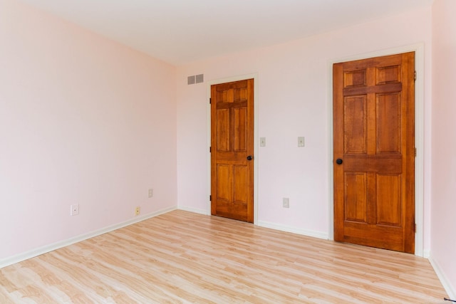 empty room featuring baseboards, visible vents, and light wood-type flooring
