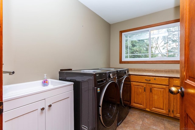 clothes washing area featuring washing machine and clothes dryer, cabinet space, and a sink