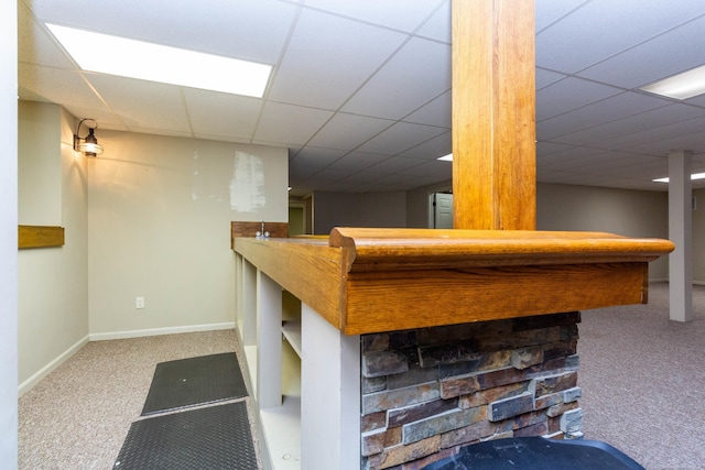 interior space with a paneled ceiling, baseboards, carpet, and a bar