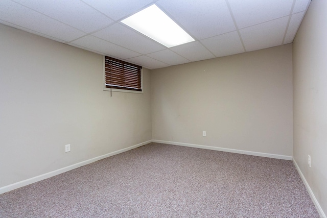 spare room with carpet floors, a drop ceiling, and baseboards