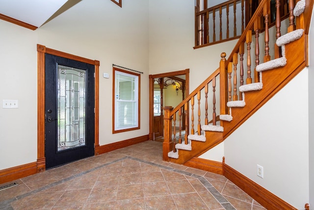 entrance foyer with visible vents, baseboards, a high ceiling, stairway, and ornamental molding