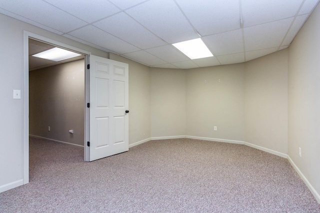 carpeted empty room with baseboards and a drop ceiling