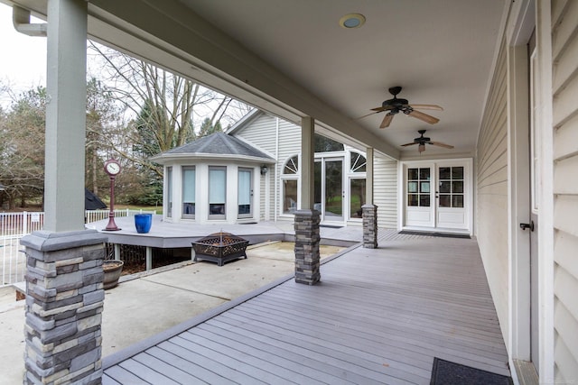 wooden deck with a fire pit, a patio, ceiling fan, and french doors