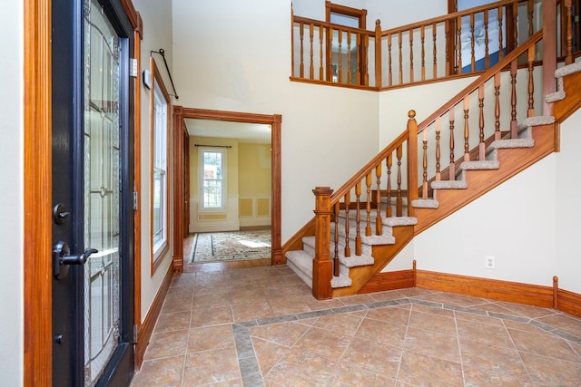 entryway with baseboards, a towering ceiling, and stairs