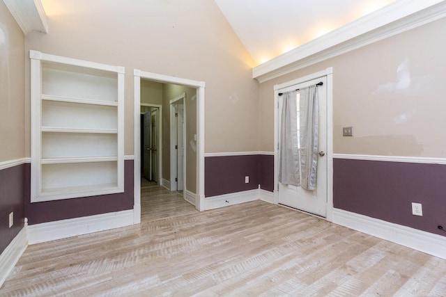 empty room with vaulted ceiling, baseboards, and wood finished floors