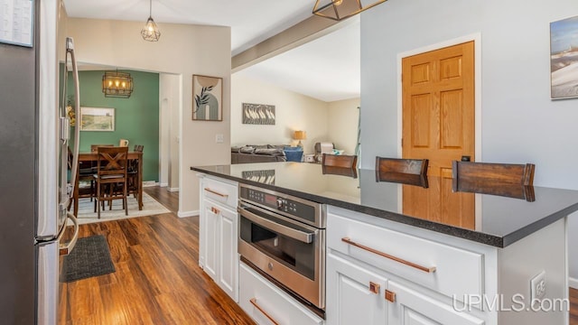 kitchen with white cabinets, dark countertops, dark wood-style floors, and stainless steel appliances