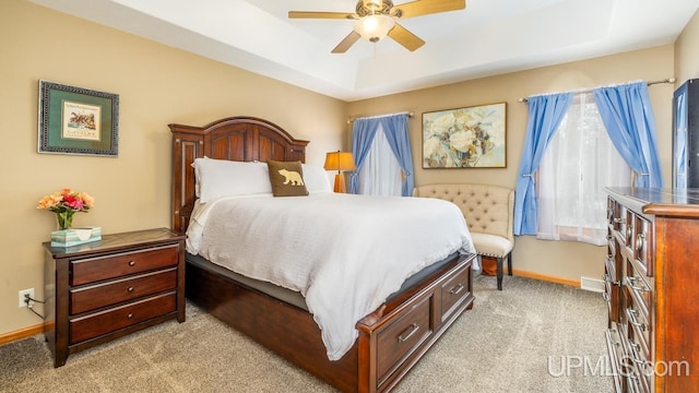 bedroom with light colored carpet, baseboards, a ceiling fan, and a raised ceiling