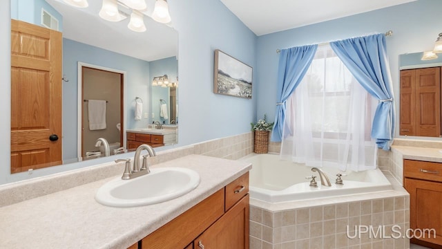 bathroom featuring a bath, a sink, and two vanities