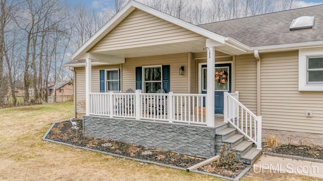 view of front of home featuring a porch, a front lawn, and a shingled roof