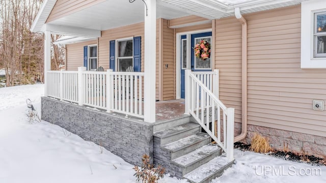 snow covered property entrance with covered porch