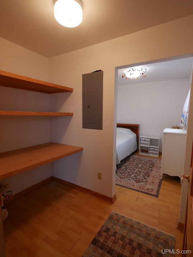 unfurnished bedroom featuring baseboards, wood finished floors, and electric panel