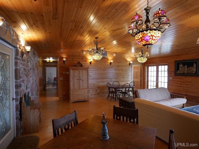 dining room featuring wooden ceiling, wood finished floors, a chandelier, and wooden walls