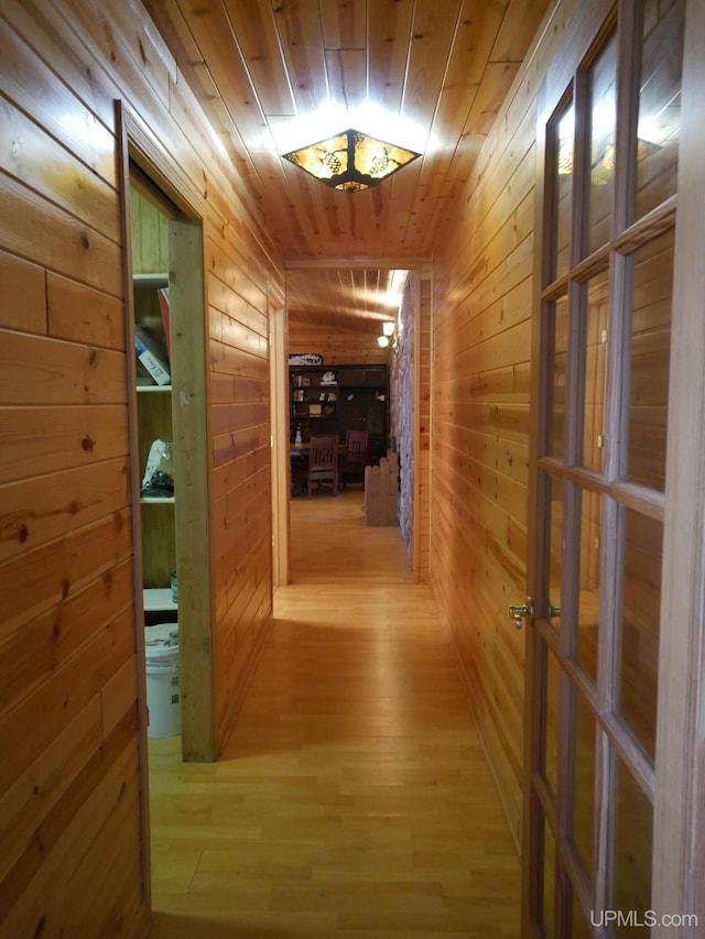 hall featuring wood finished floors, wooden ceiling, and wood walls