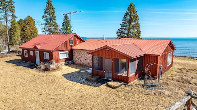 rear view of house featuring a sunroom, board and batten siding, and metal roof