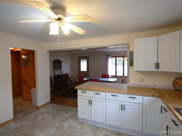 kitchen featuring wood counters, a peninsula, ceiling fan, and white cabinets