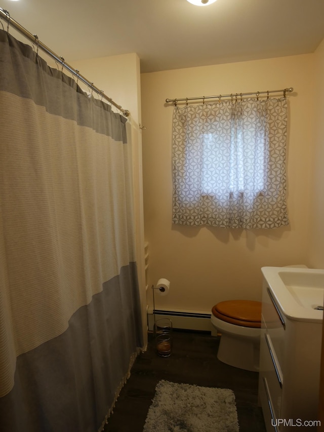bathroom featuring baseboard heating, wood finished floors, vanity, and toilet
