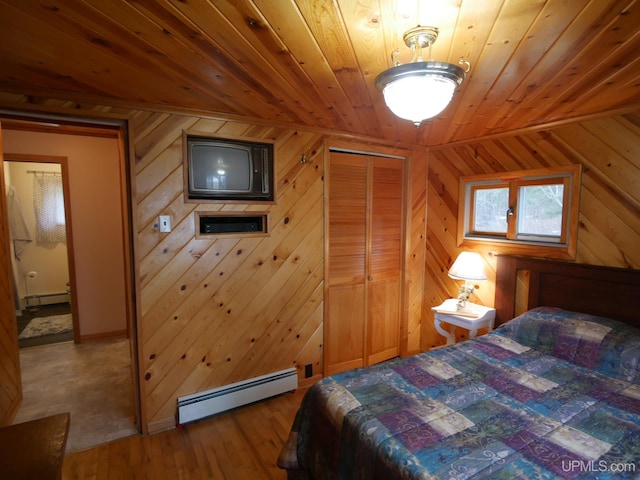 bedroom featuring a baseboard heating unit, wood-type flooring, a closet, and wood ceiling