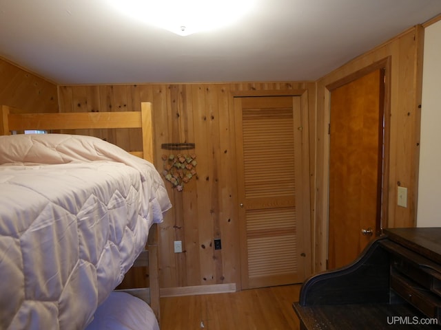 bedroom featuring wood walls, wood finished floors, and a closet