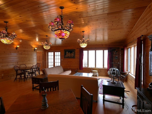 dining room featuring wood finished floors, wood walls, an inviting chandelier, and wooden ceiling