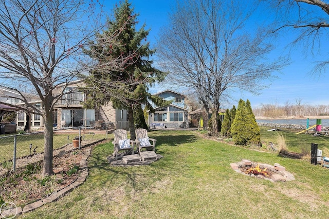 view of yard with fence, an outdoor fire pit, and a water view