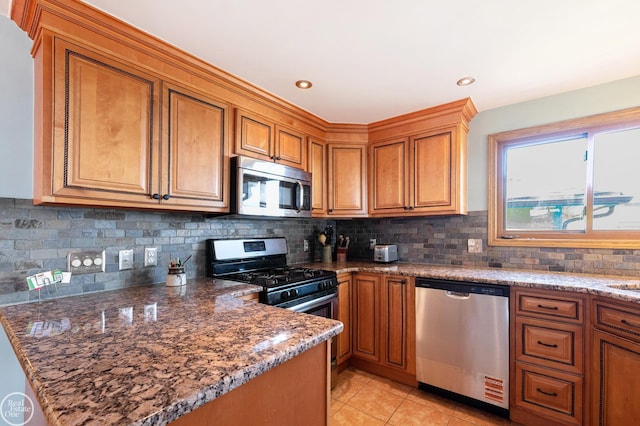 kitchen featuring brown cabinetry, backsplash, and appliances with stainless steel finishes