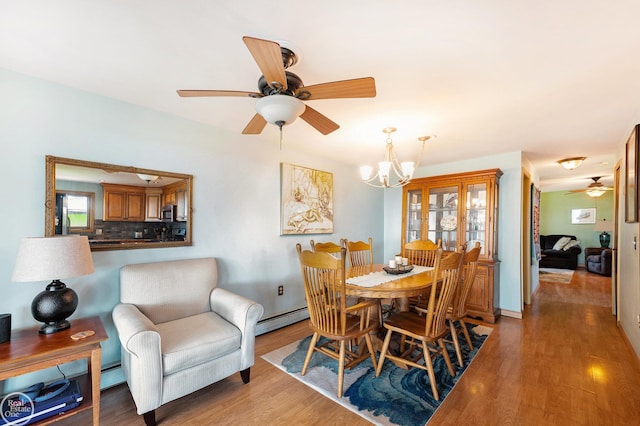 dining area featuring a baseboard heating unit, light wood finished floors, and ceiling fan with notable chandelier