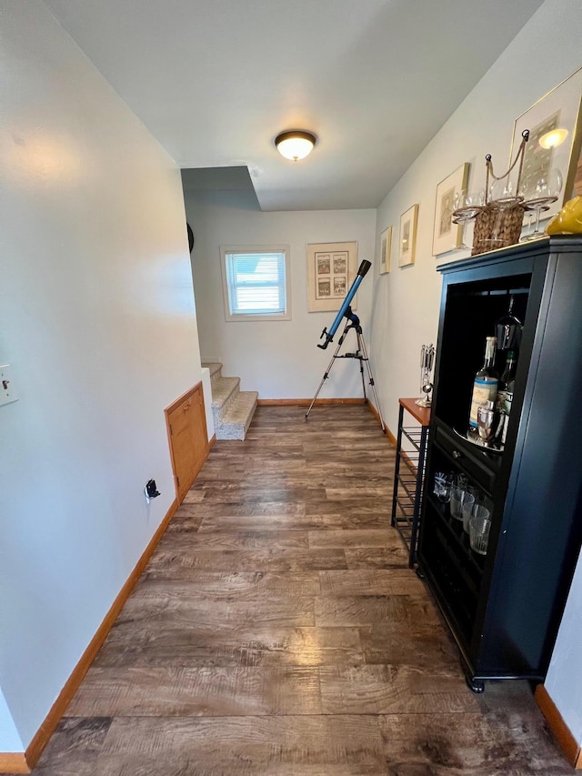 hallway with dark wood finished floors, baseboards, and stairs