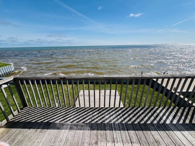 wooden deck featuring a beach view and a water view