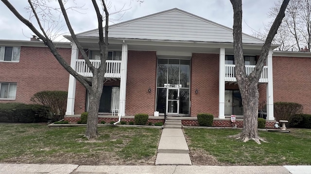 neoclassical home featuring a front lawn, covered porch, and brick siding