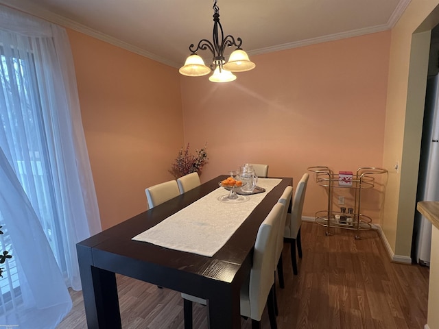 dining room with baseboards, ornamental molding, wood finished floors, and an inviting chandelier