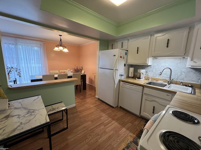 kitchen with white cabinets, backsplash, wood finished floors, white appliances, and ornamental molding
