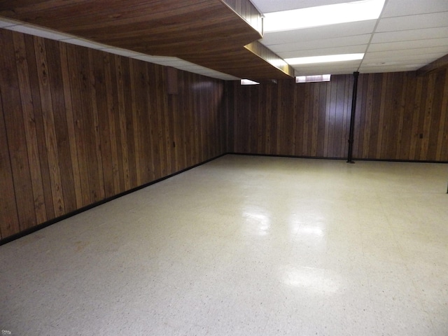 finished basement featuring wooden walls and light floors