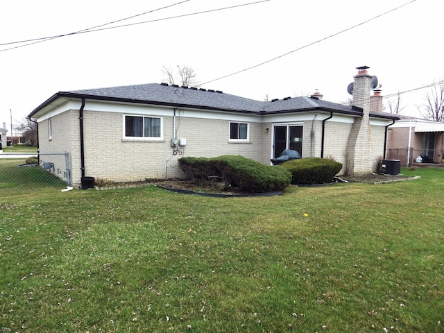 rear view of property with brick siding, fence, and a yard