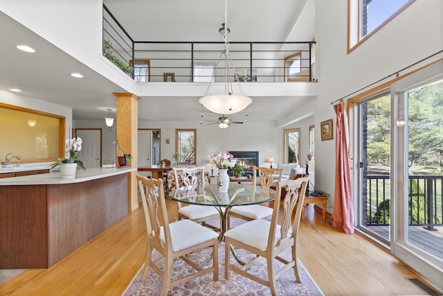 6728 Frith Rd, Smiths Creek, MI 48079 - dining area with a warm lit fireplace, a towering ceiling, ceiling fan, and light wood-style floors