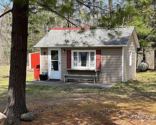 view of front of property featuring an outdoor structure and roof with shingles