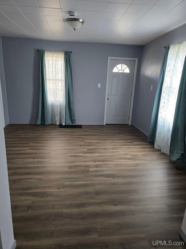 foyer entrance with a wealth of natural light, dark wood-type flooring, and baseboards