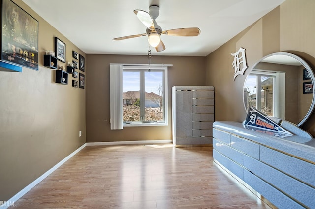 unfurnished bedroom with arched walkways, ceiling fan, baseboards, and wood finished floors