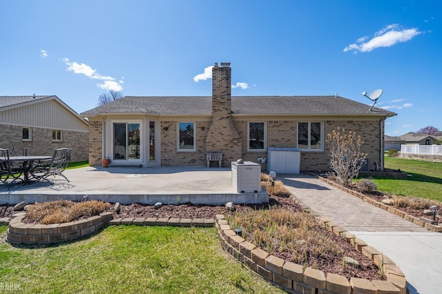 back of property featuring a patio area, a lawn, a chimney, and brick siding