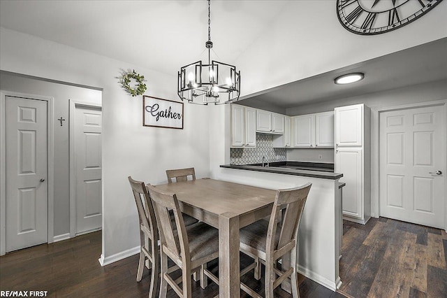 dining space with dark wood finished floors, lofted ceiling, baseboards, and a notable chandelier