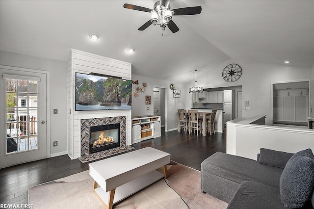 living room featuring lofted ceiling, wood finished floors, baseboards, a fireplace, and ceiling fan with notable chandelier