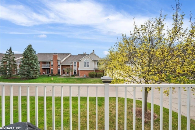 view of front facade featuring a balcony, a front yard, and brick siding