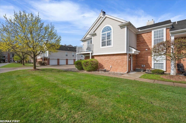 view of front of property with driveway, central AC, a chimney, brick siding, and a front yard