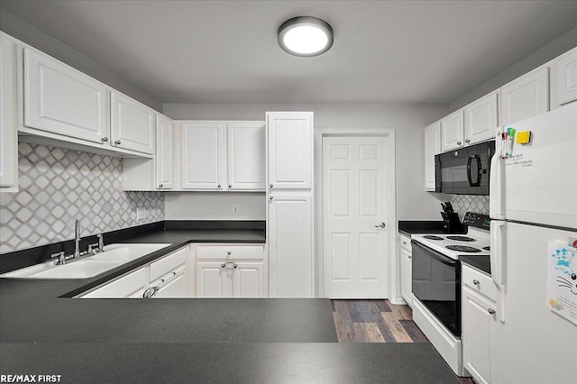 kitchen with dark countertops, black microwave, range with electric stovetop, white cabinets, and freestanding refrigerator
