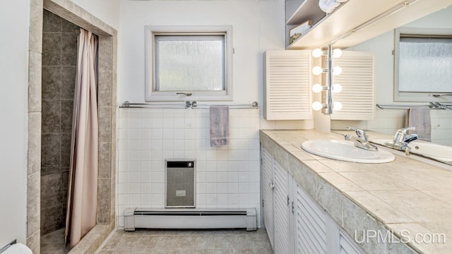 bathroom featuring a tile shower, vanity, tile patterned floors, and baseboard heating