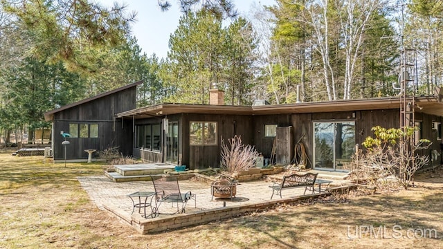 rear view of house featuring a fire pit, a chimney, and a patio