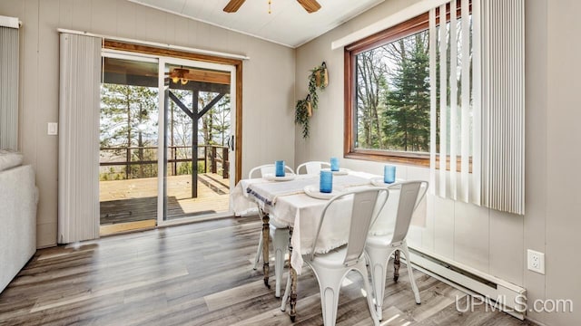 dining room with a baseboard heating unit, wood finished floors, and a ceiling fan