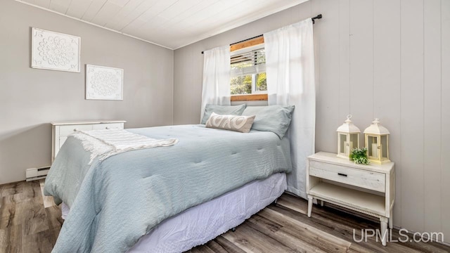 bedroom featuring wood finished floors and a baseboard radiator